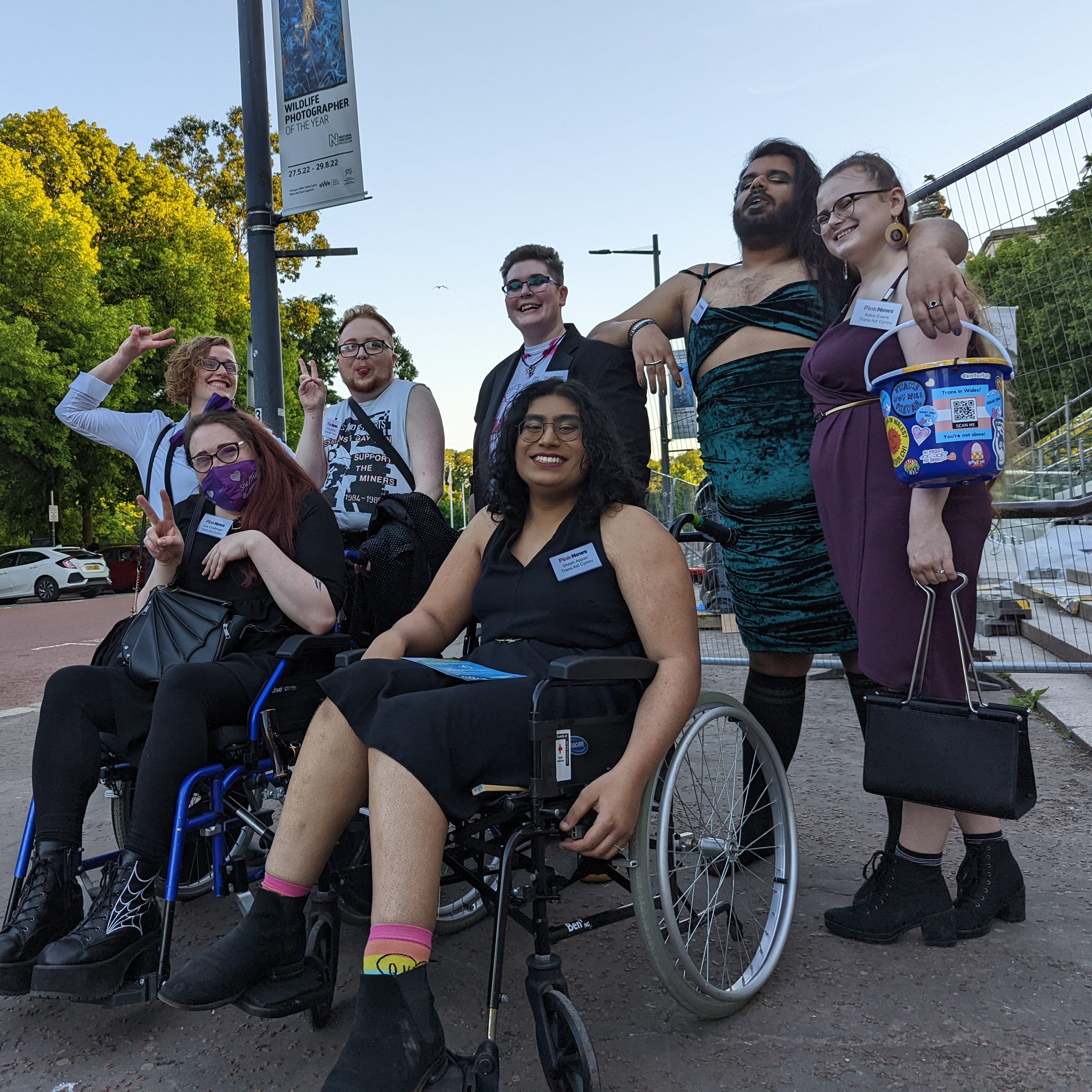 people dressed glamorously, with 2 in wheelchairs, posing for a photo outside the venue